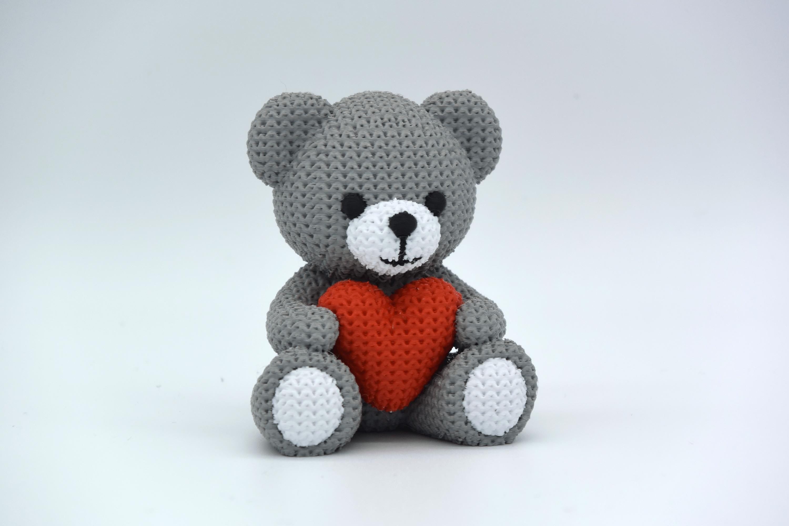 Gray crochet teddy bear with a red heart on a white background